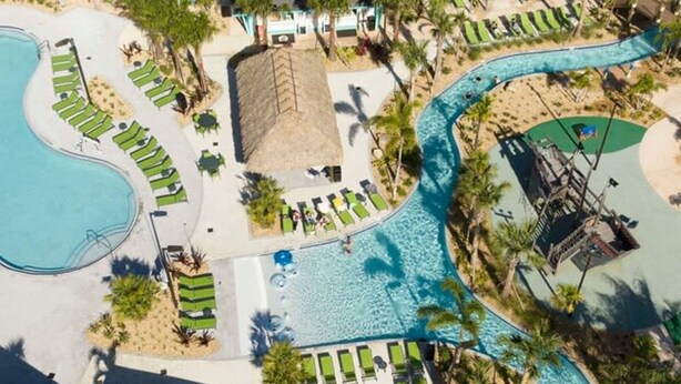 An aerial view of a resort with multiple swimming pools, lounge areas, and palm trees. - 2681 Stunning 4BD Home Perfect For Your Family (Kissimmee)