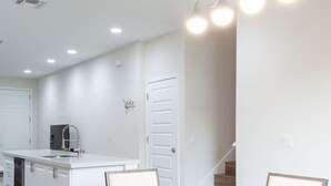 A modern kitchen with white cabinetry, a wooden dining table, and a built-in oven. - 4449 Lovely 5BD For Your Family (Kissimmee)