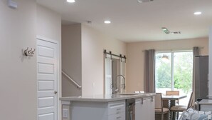 A modern kitchen with a central island, a dining area with a table and chairs, and a cozy seating area with a sofa. - 4449 Lovely 5BD For Your Family (Kissimmee)