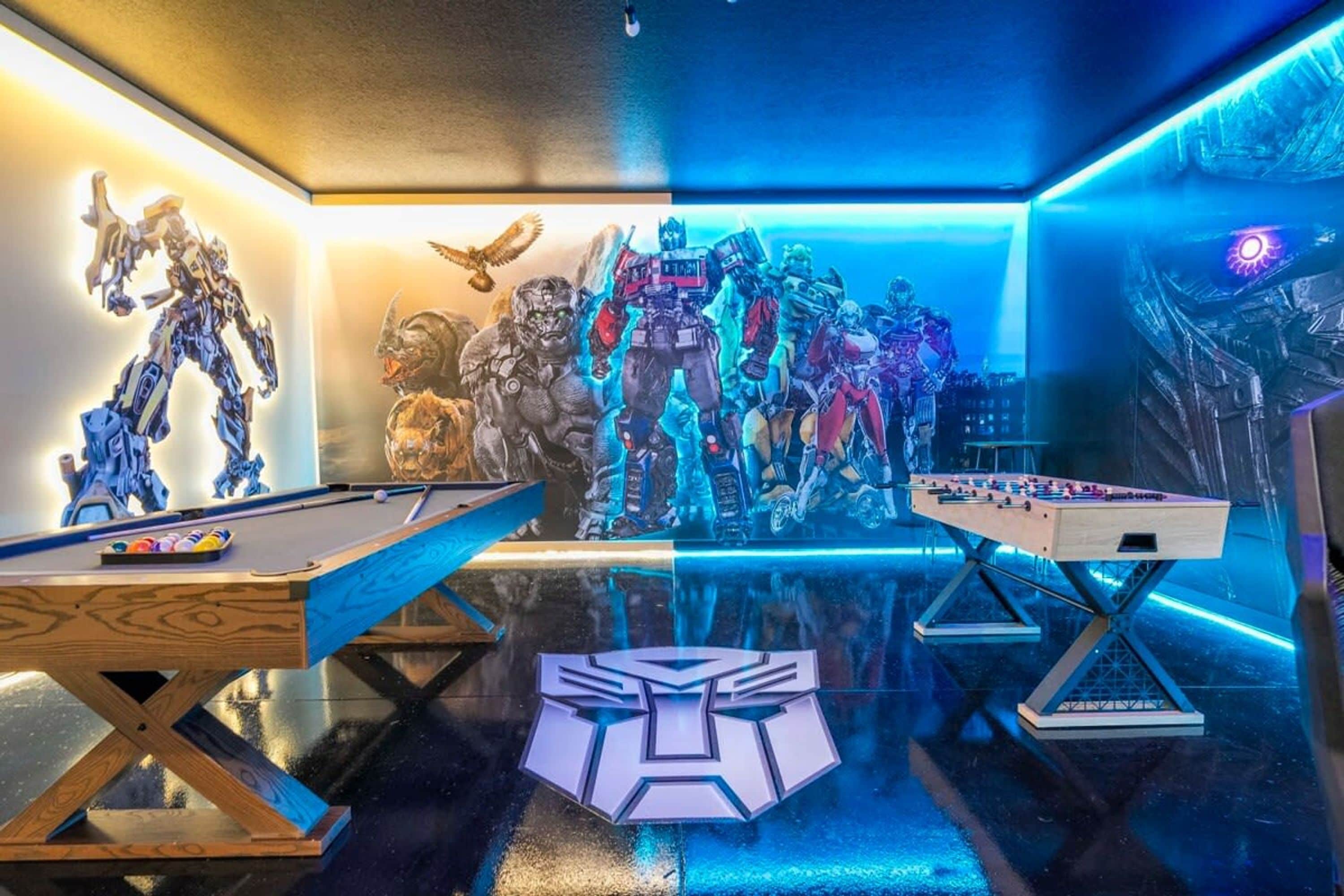 A room with a pool table, foosball table, and a large logo on the floor.