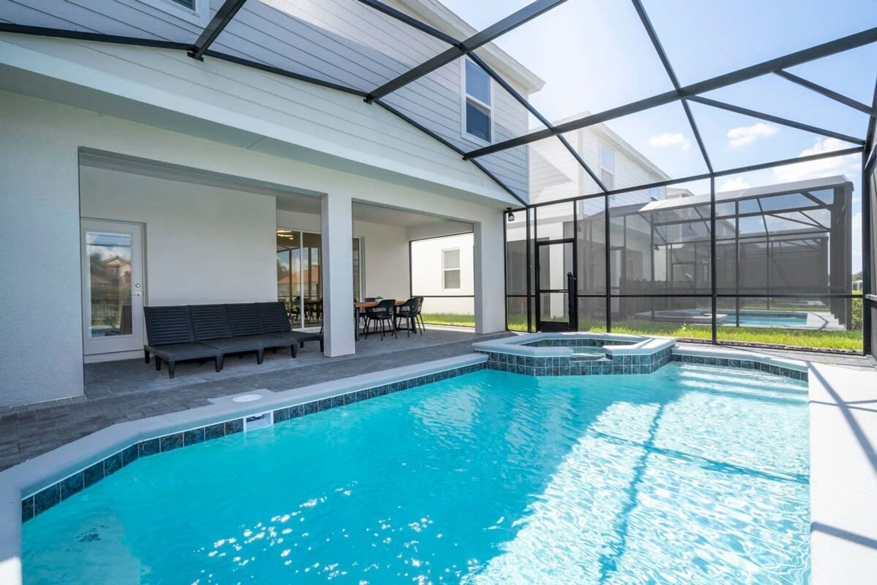 Une piscine entourée de parois en verre, un banc et une table avec des chaises.