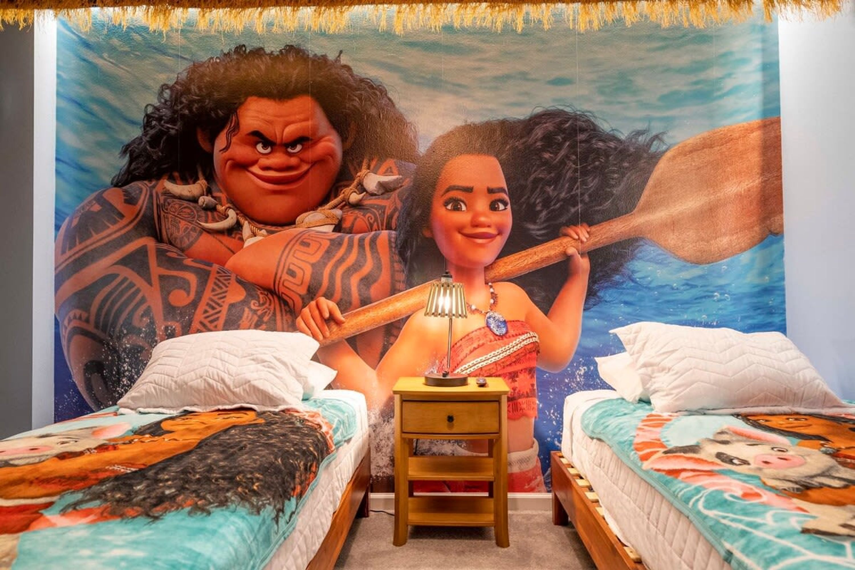 A bedroom with two beds, a nightstand, and a mural on the wall.