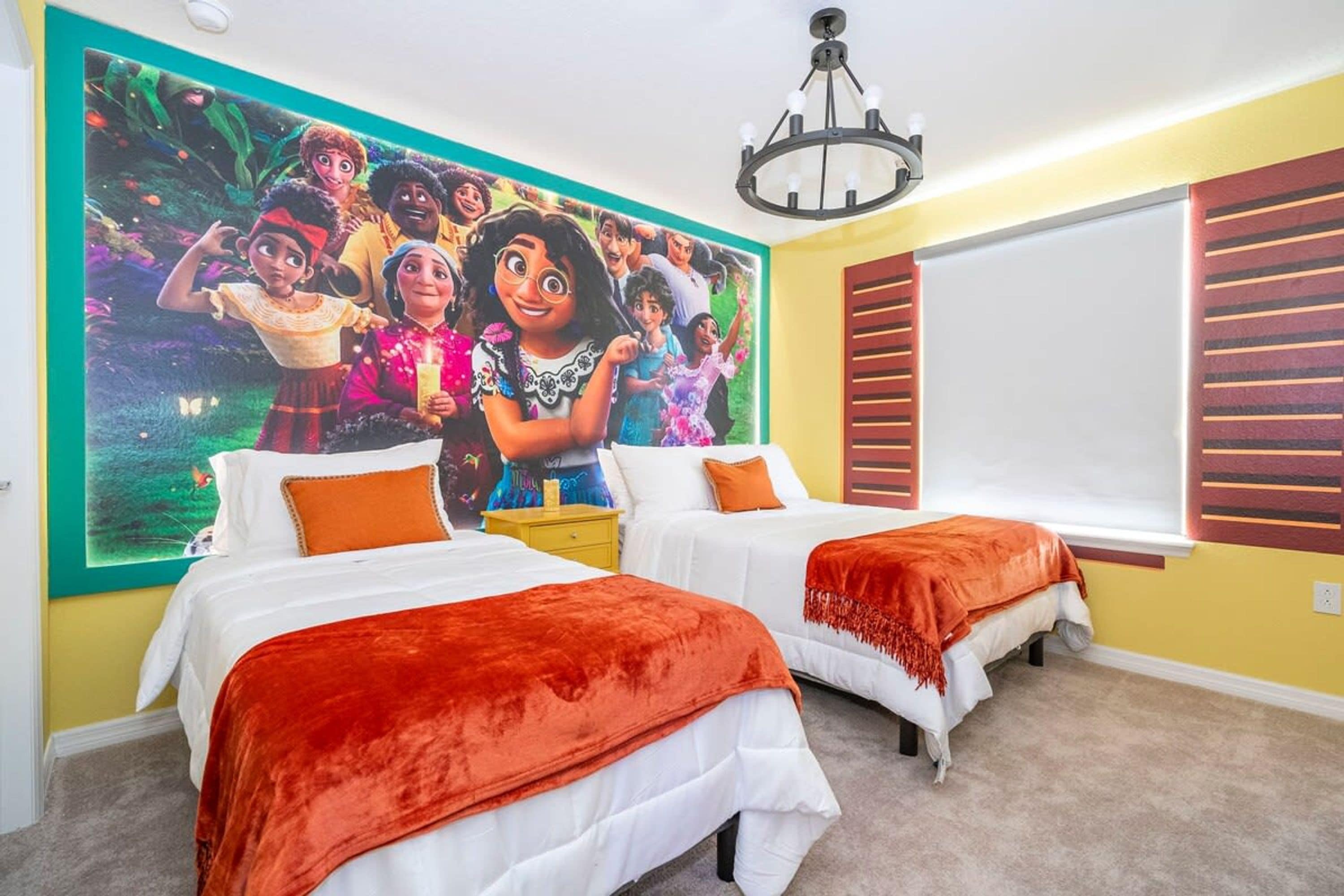 A bedroom with two beds, a mural on the wall, a window with blinds, and a chandelier.
