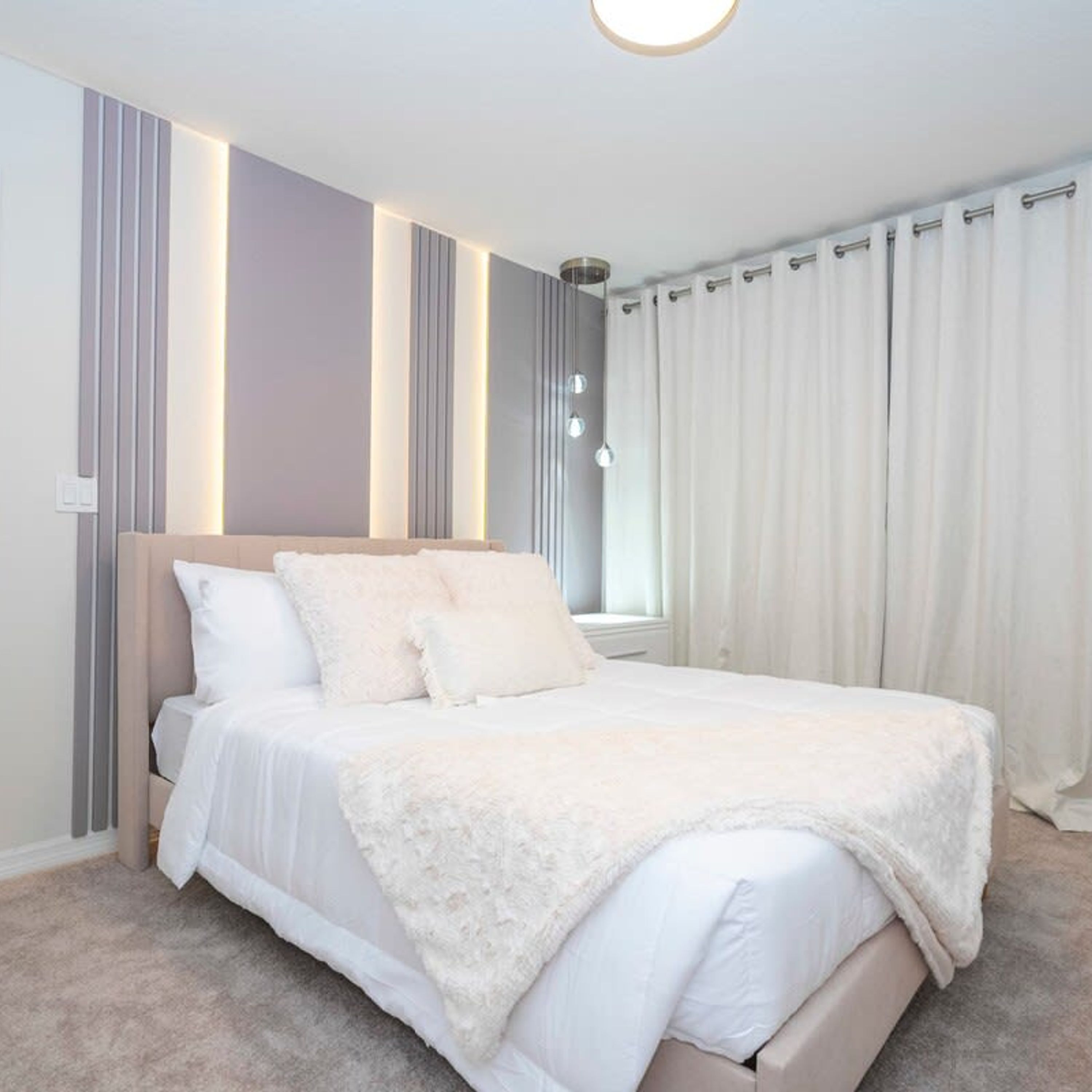 Une chambre à coucher avec un lit, des rideaux et un luminaire au plafond.