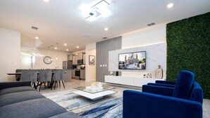 A modern living room with a sofa, a coffee table, and a TV mounted on the wall.