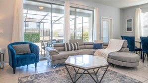 A modern living room with a grey sectional sofa, a blue armchair, and a white coffee table.