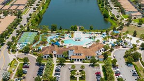 An aerial view of a resort with a central building, a swimming pool, and a tennis court.