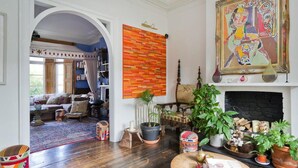 A cozy living room with a fireplace, a colorful abstract painting, and a bookshelf. - Stylish 5 Bed House in St John s Wood Maida Vale (London)
