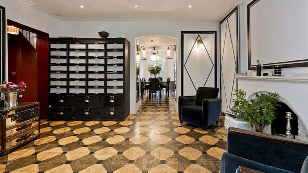 A hotel lobby with a check-in counter, a seating area, and a patterned floor. - Stylish 5 Bed House in St John s Wood Maida Vale (London)