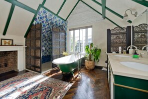 Une salle de bain avec une baignoire sur pieds, un lavabo et une fenêtre.
