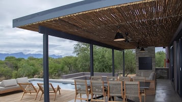 Relax in a shaded outdoor lounge with comfortable seating and a scenic pool view.