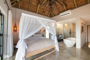 Ein Schlafzimmer mit Baldachinbett, einer großzügigen Badewanne und Deckenventilator.