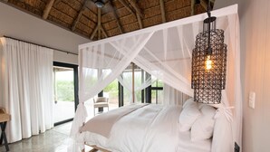 Une chambre à coucher avec un lit à baldaquin, un luminaire suspendu et une vue sur l’extérieur.