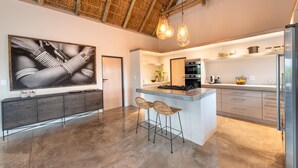 Une cuisine moderne dotée d’un grand îlot central, de tabourets de bar, d’un coin repas et d’un grand tableau accroché au mur.