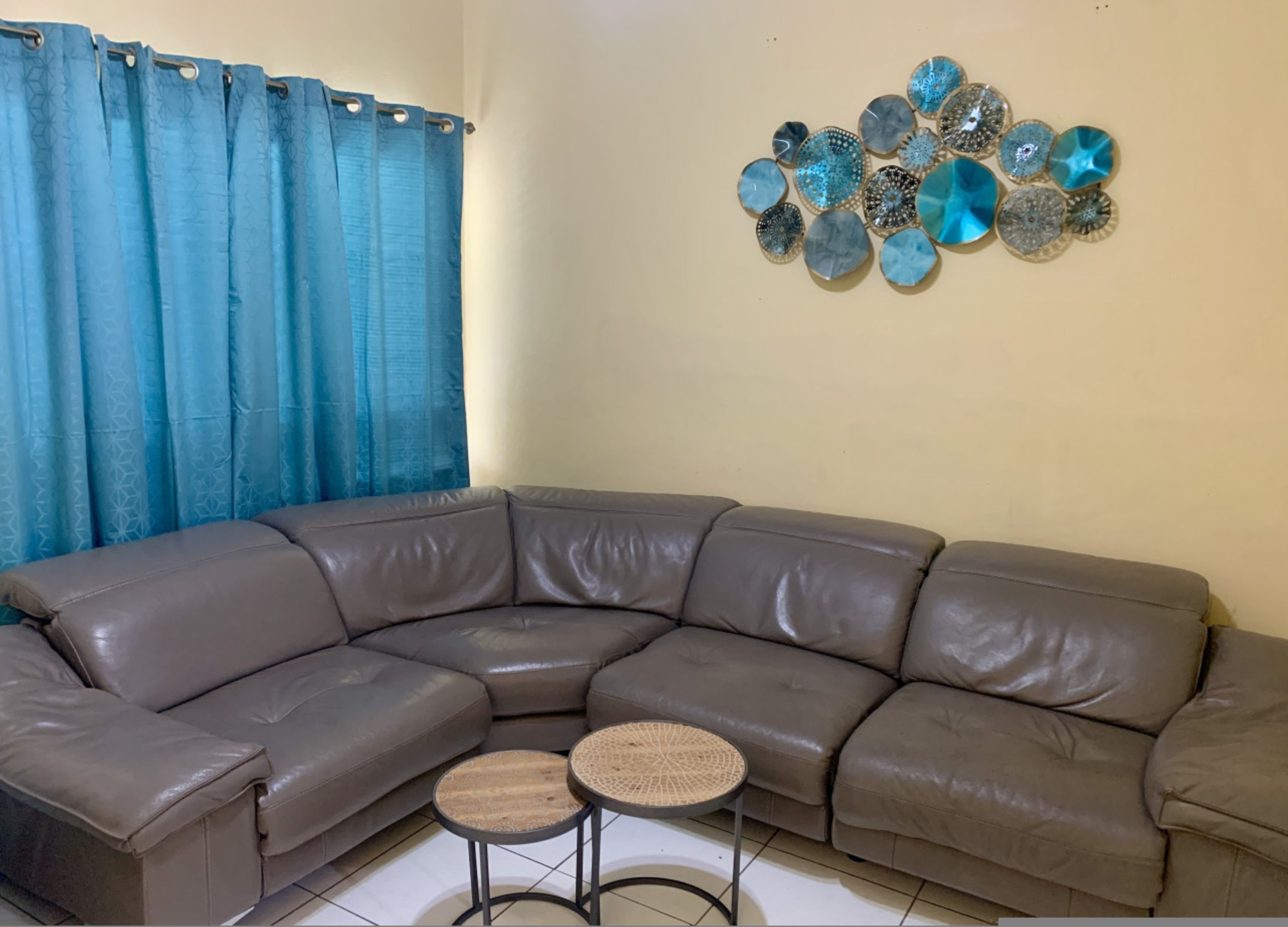 A brown leather sectional sofa with a small round table in front.