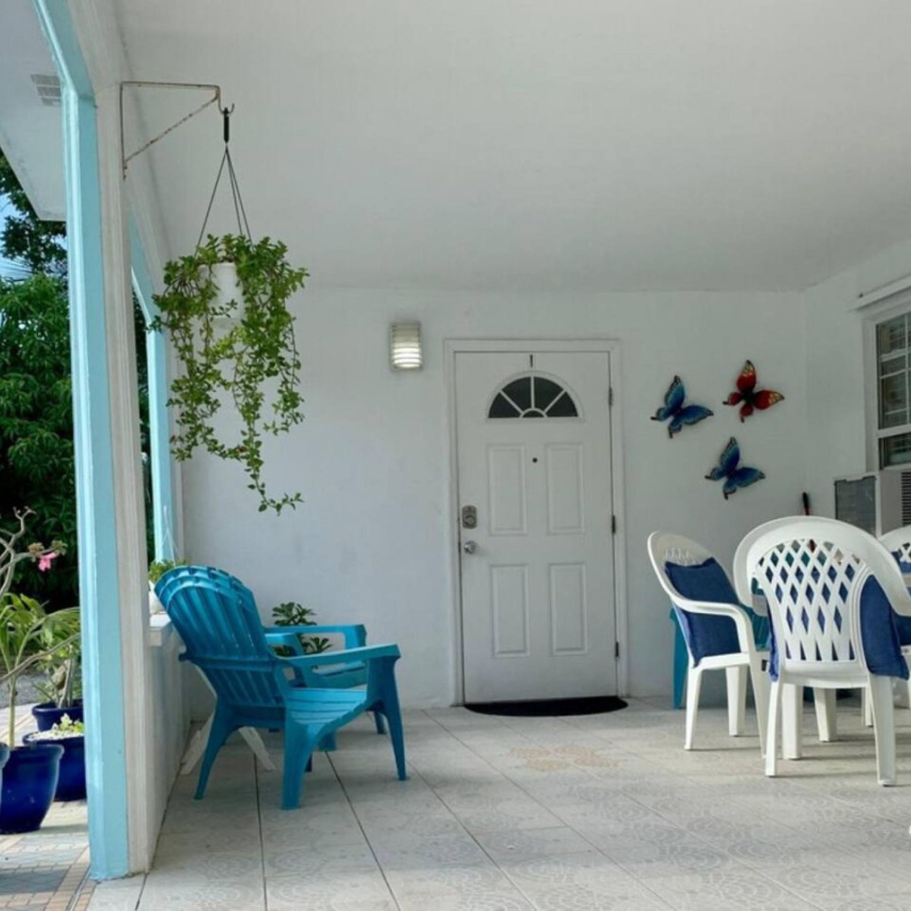 Een overdekte veranda met blauwe stoelen en een witte deur.