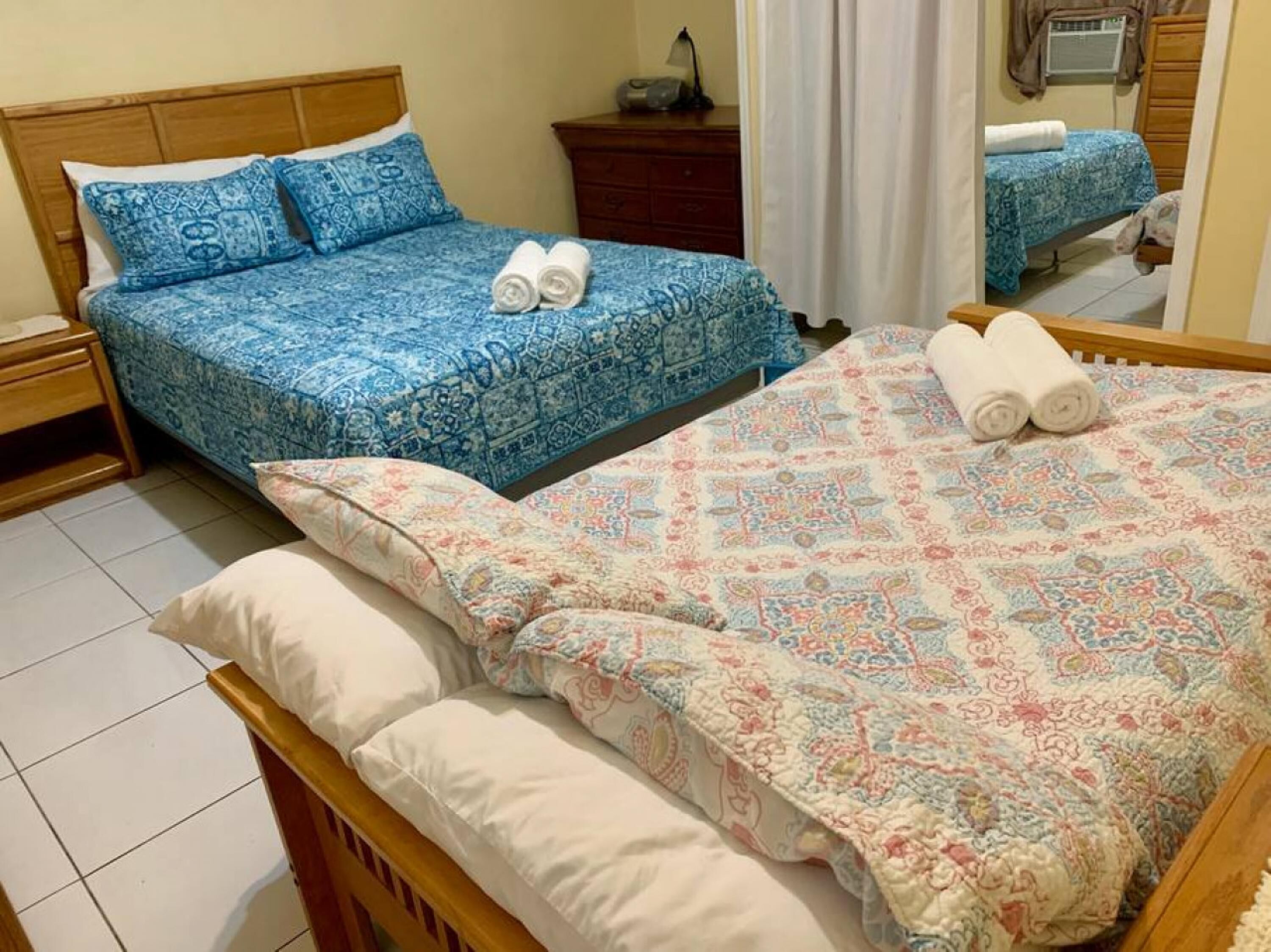 Un dormitorio con dos camas, cada una con ropa de cama estampada y toallas enrolladas.
