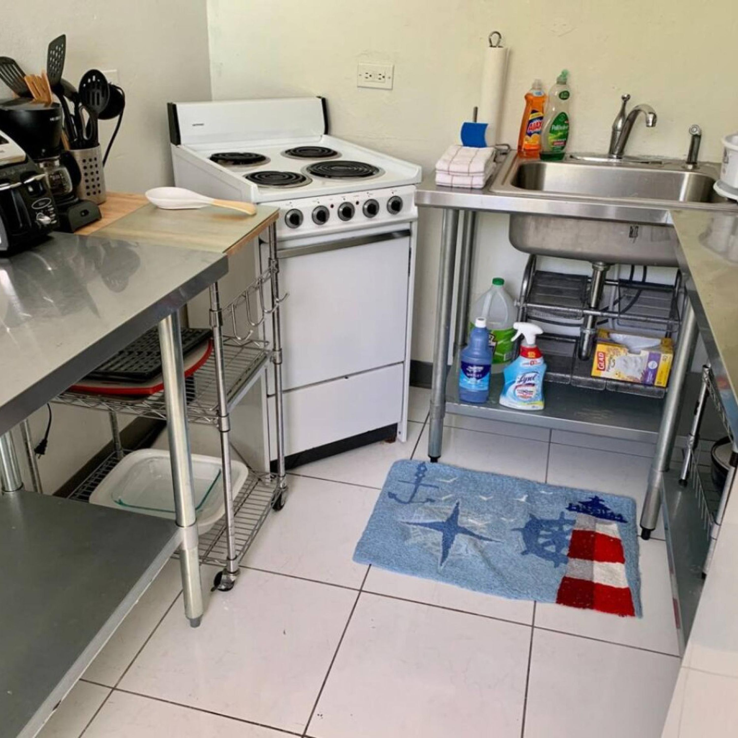 A compact kitchen with a stove, sink, and various kitchen utensils.