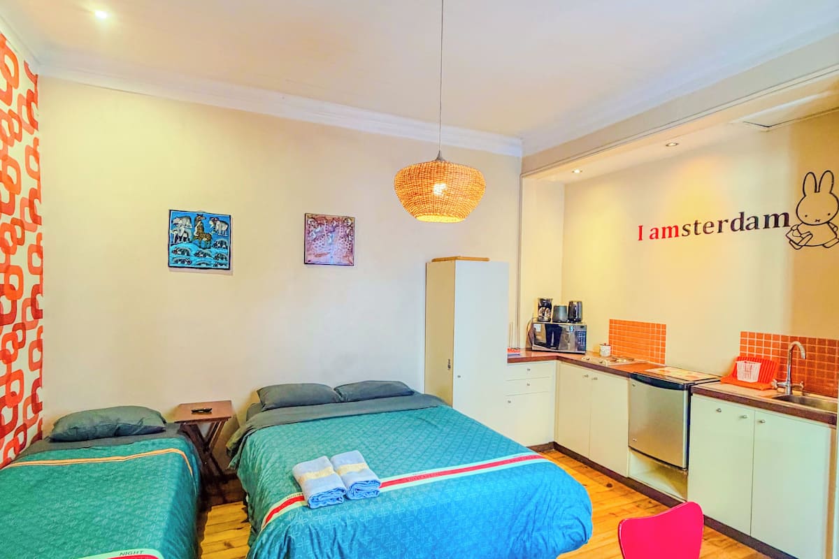 A hotel room with two beds, a kitchenette, and a dining area.