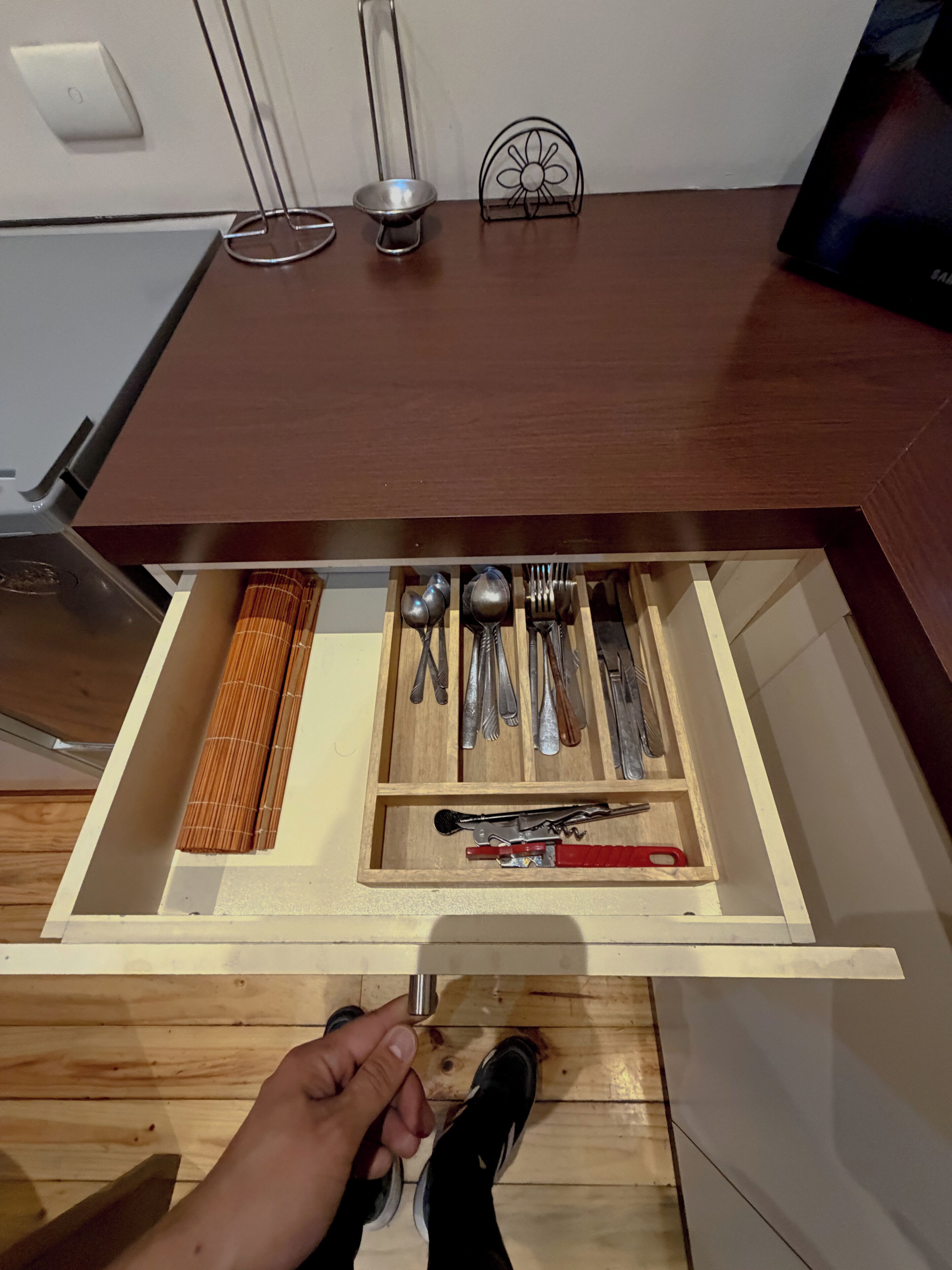 A drawer with utensils and a red-handled tool.