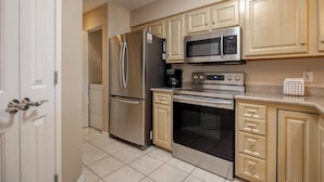 Uma cozinha moderna com eletrodomésticos de aço inoxidável, armários de madeira e piso revestido de azulejos.