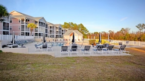 Um hotel com piscina, espreguiçadeiras e área coberta.