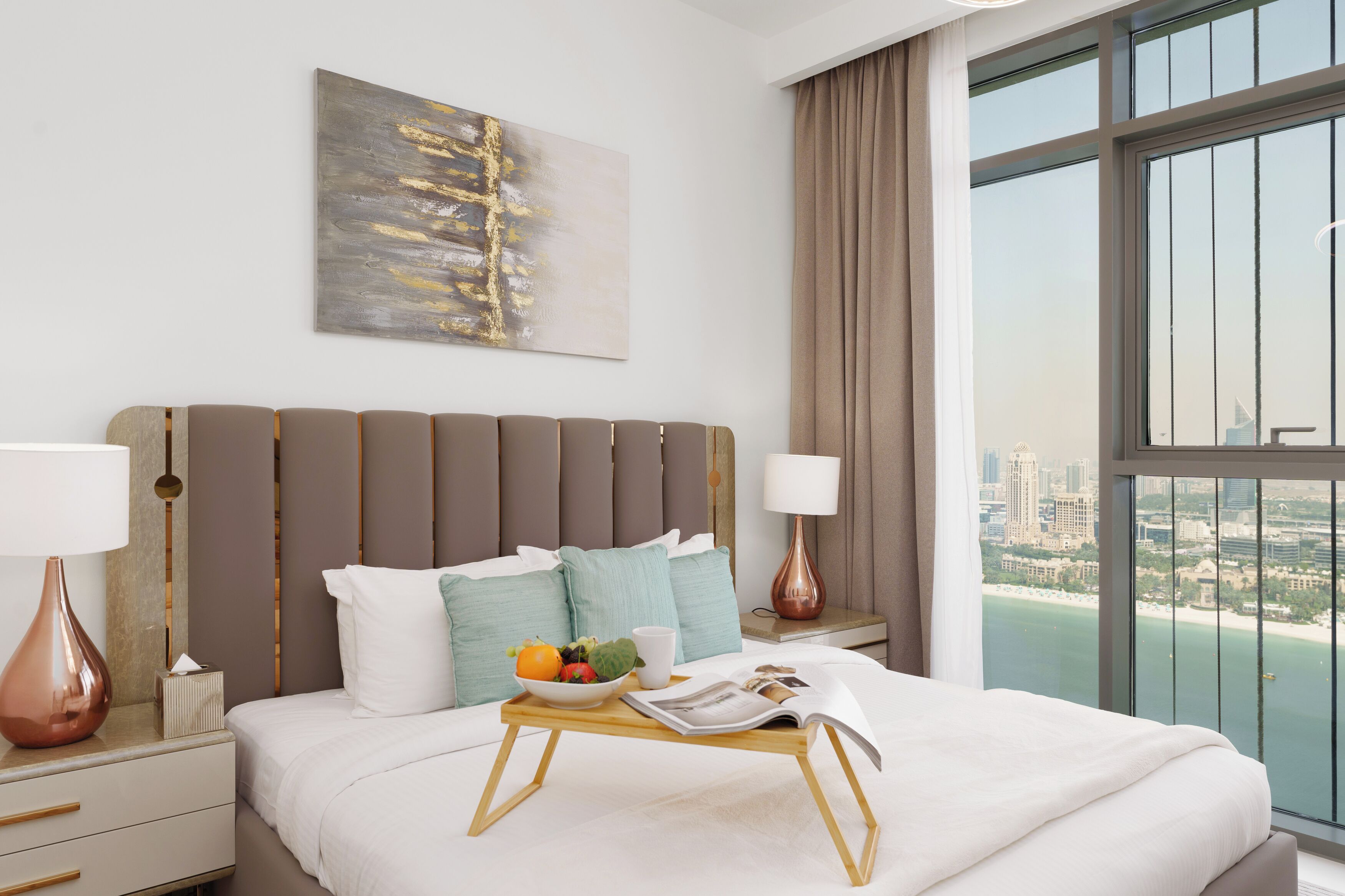 Habitación de hotel moderna con una cama grande, vista a la ciudad y una bandeja de desayuno en la cama.