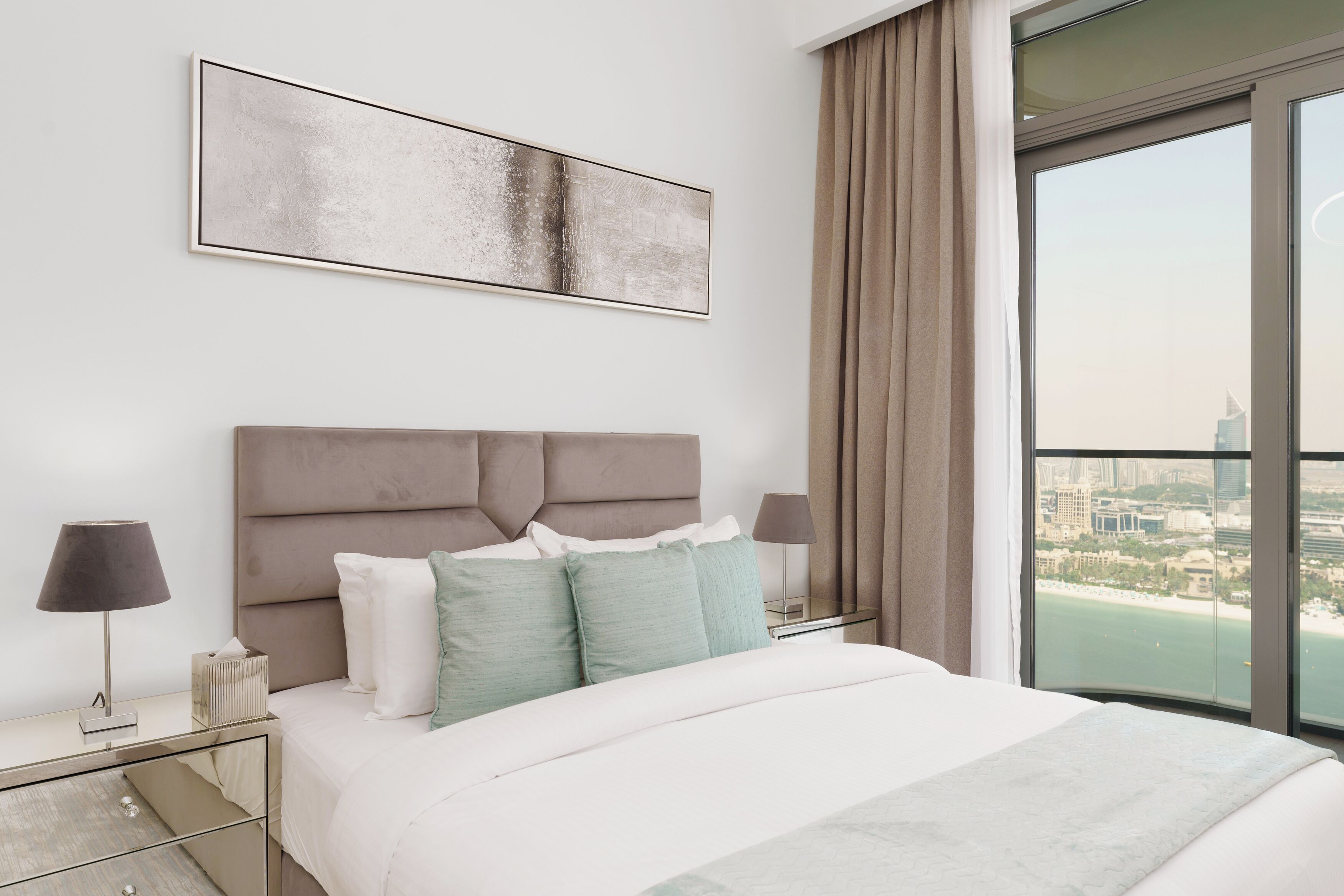Une chambre d’hôtel moderne avec un grand lit, une vue sur la ville et un décor minimaliste.