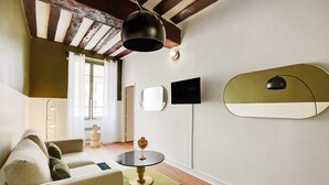 A modern living room with a sofa, a round table, and a television mounted on the wall. - Résidence Paris SEVRES (Paris)