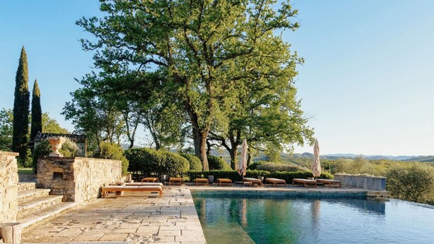 A poolside area with stone steps, lounge chairs, and a view of the landscape. - Le Porciglia by Boutique (Colle di Val d'Elsa)