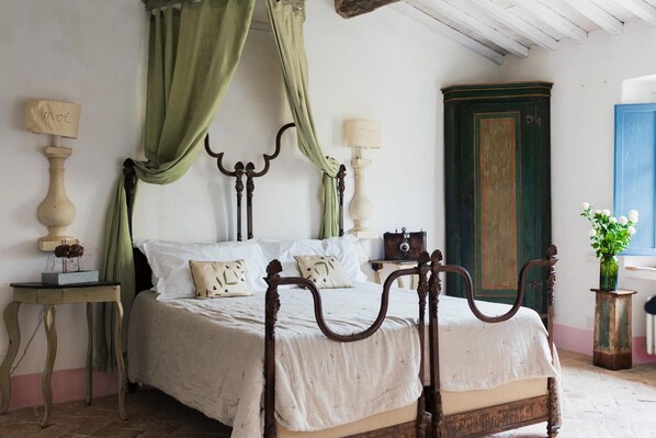 Un lit à baldaquin, une armoire en bois, une petite table avec une lampe et un vase rempli de fleurs.