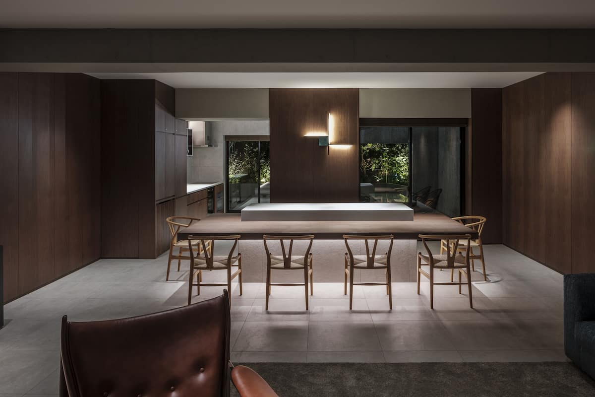 Un espace repas moderne avec une longue table et des chaises, un canapé et un téléviseur.