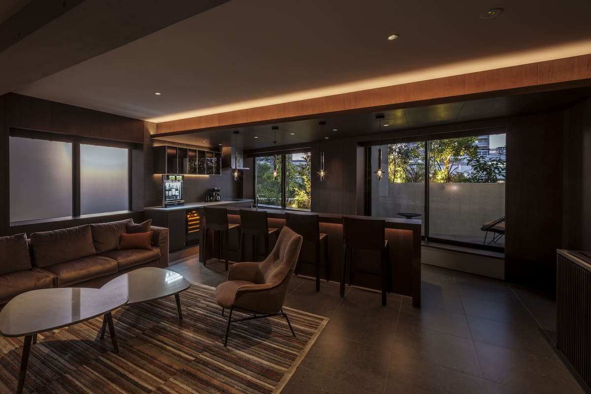 Un salon moderne avec un canapé, une table basse et un coin bar équipé de tabourets.