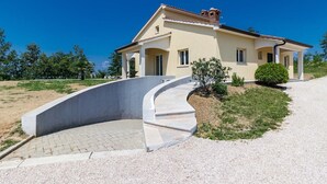 Ein zweistöckiges Haus mit einer geschwungenen Auffahrt, die zu einer Veranda führt.