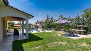 Ein Garten mit Pool, Sitzgelegenheit im Freien und Grillplatz.