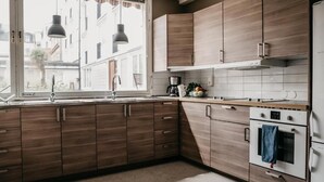 Una cocina moderna con armarios de madera, horno empotrado y ventana con vistas a la calle.