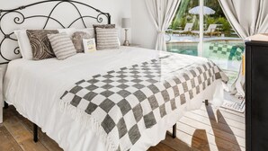 Un dormitorio con cama, cabecera, un letrero en la pared, una ventana con cortinas y vista a una piscina al aire libre.