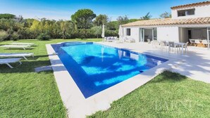 A rectangular swimming pool with clear blue water, surrounded by a well-maintained lawn and white lounge chairs. - Villa Contemporaine Neuve Plage a Pieds Piscine Chauffée (Saint-Tropez)