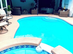 Una piscina con bordo piastrellato, circondata da arredi da esterno e un'area coperta con posti a sedere.