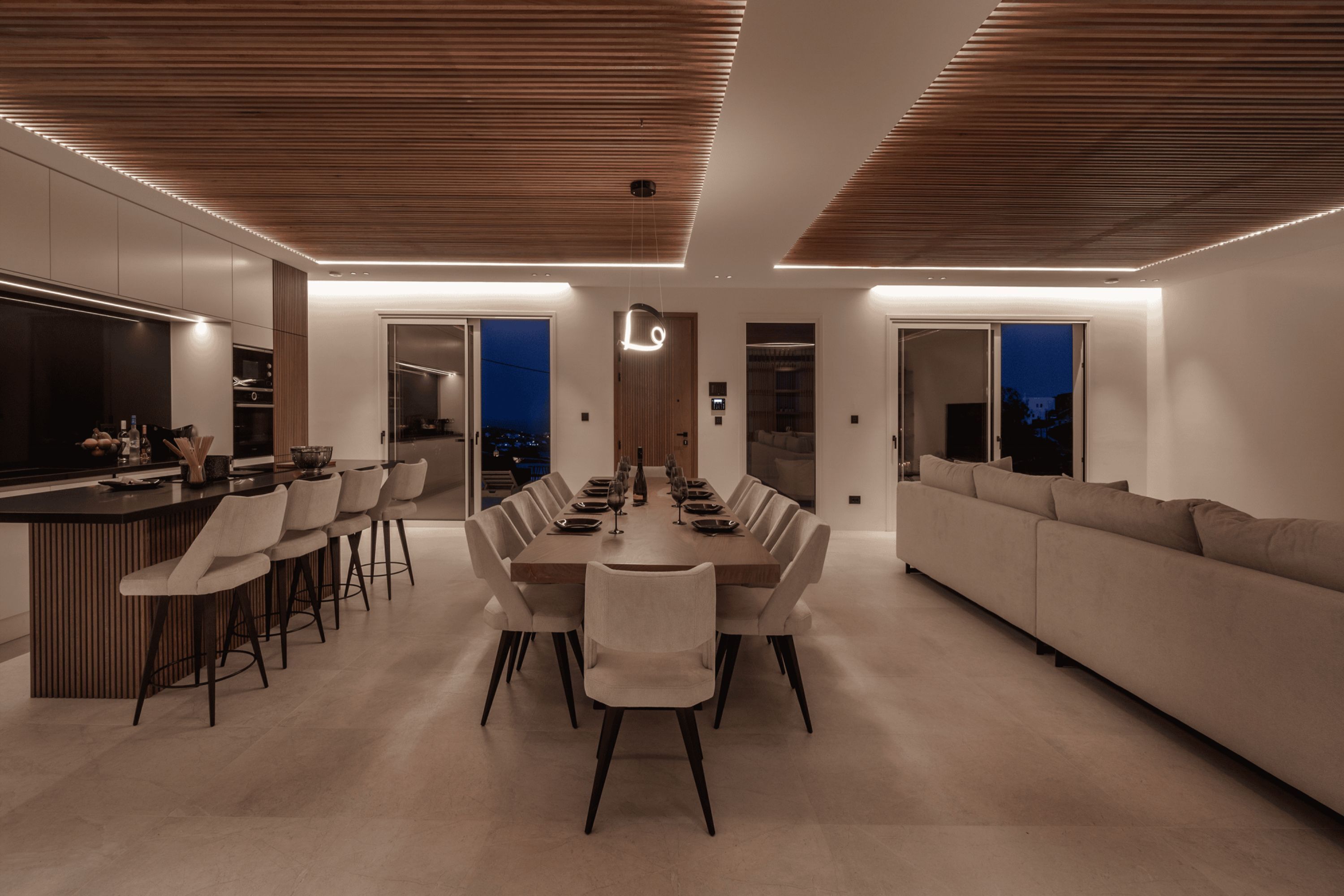 A modern dining area with a long table, multiple chairs, and a bar counter.