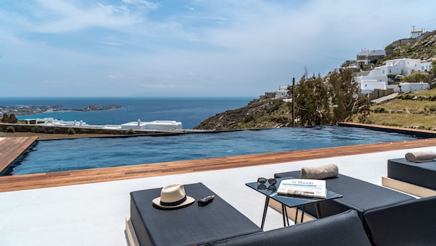 A poolside area with a view of the sea and white buildings. - Elit Villa Psarou Mykonos (Mykonos)