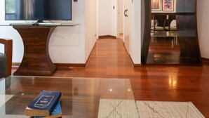 A modern living room with a flat-screen TV, a wooden coffee table, and a book. - w Upscale 2BR Near Larcomar Miraflores (Lima)