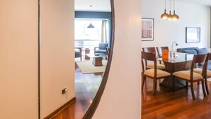 A modern living room with a dining area, featuring a large mirror, wooden flooring, and contemporary furniture. - w Upscale 2BR Near Larcomar Miraflores (Lima)
