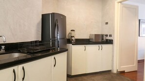 A compact kitchen with white cabinets, a black refrigerator, a microwave, and a sink with a dish rack. - w Upscale 2BR Near Larcomar Miraflores (Lima)