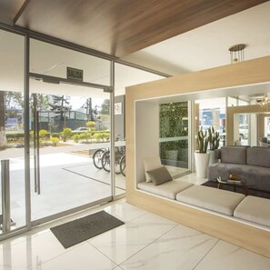Uma área de recepção moderna com um sofá, uma mesa de centro e um vaso de planta.