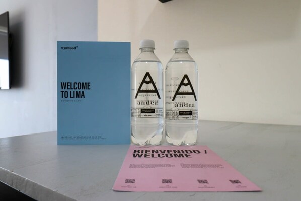 A welcome sign, two water bottles, and a pink welcome card on a table.