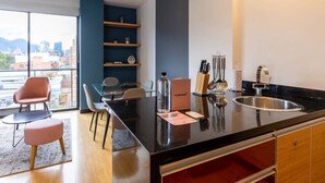 A modern kitchen with a black countertop, a sink, and a dining area with chairs and a table. - w Vibrant 1BR in Chico (Bogotá)