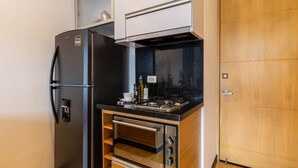 A compact kitchen with a built-in refrigerator, oven, and microwave. - w Vibrant 1BR in Chico (Bogotá)