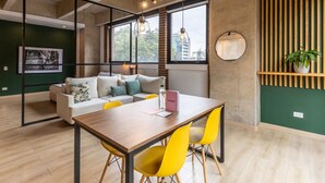 A modern living space with a wooden dining table, yellow chairs, a grey sofa, and a green accent wall. - w Radiant Loft in Parque 93 (Bogotá)