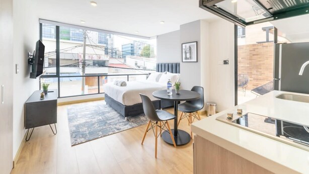 A modern hotel room with a bed, a dining table, and a kitchen area. - w Lovely Loft With Terrace in Santa Ana (Bogotá)